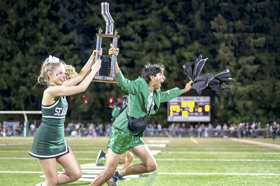 PHS cheer senior Bella Bryson and class president Alec Krishnadasan run to the stands with the winning Food Bowl trophy. A total of 44,284 food items were collected for FB4K by all three high schools.